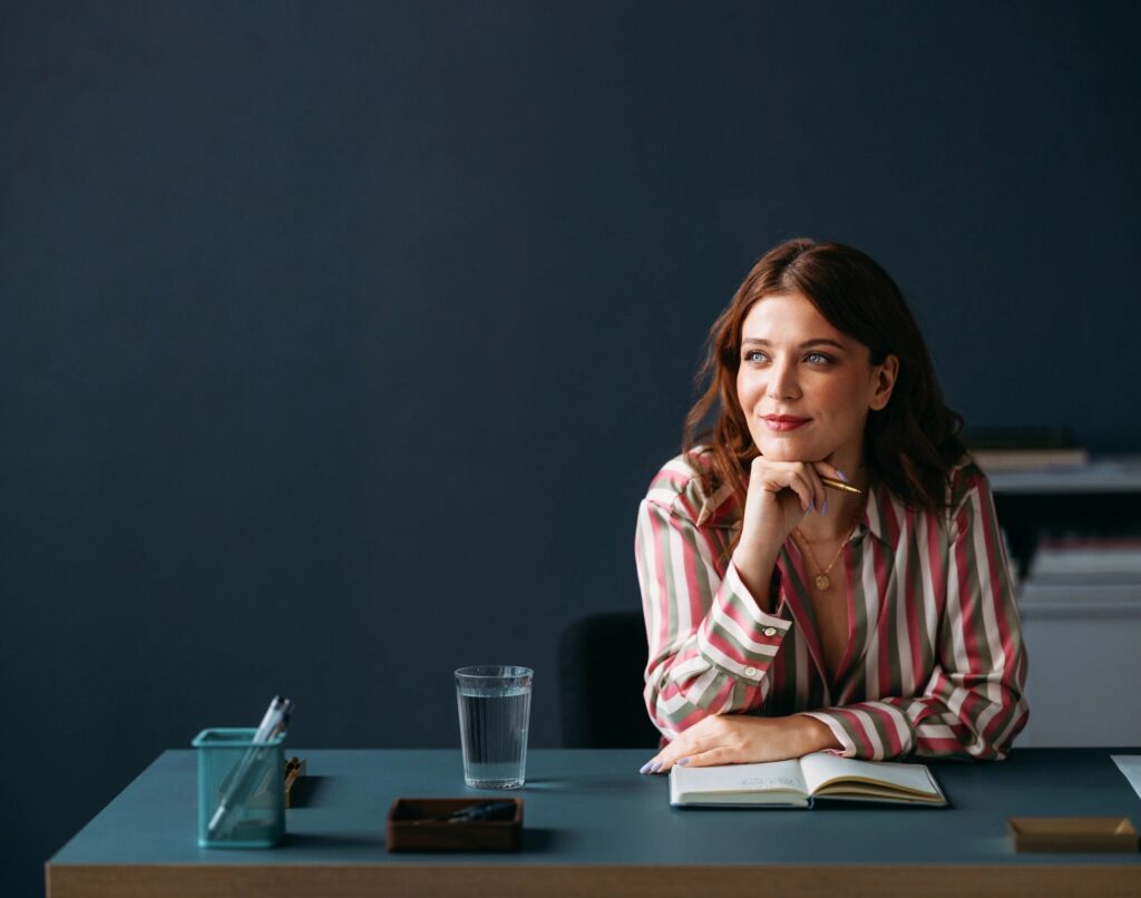 Professional Woman in Striped Shirt Smiling at Work in Office